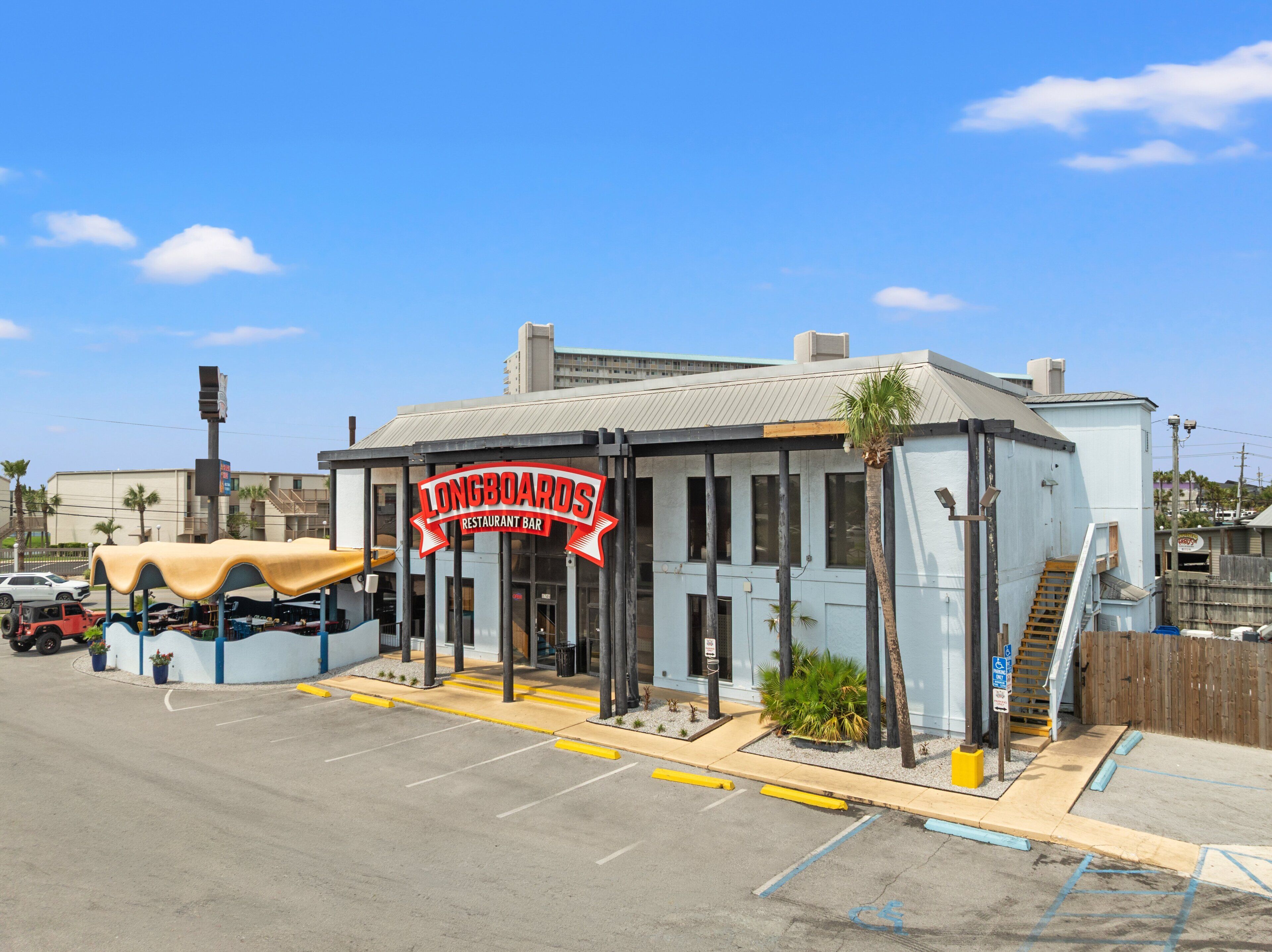 A building with a sign reading 'Longboards Restaurant Bar' and a covered outdoor seating area.