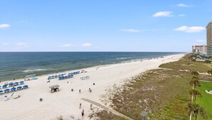 En strand med parasoller, et redder-tårn og en træpromenade, der fører hen til havet.