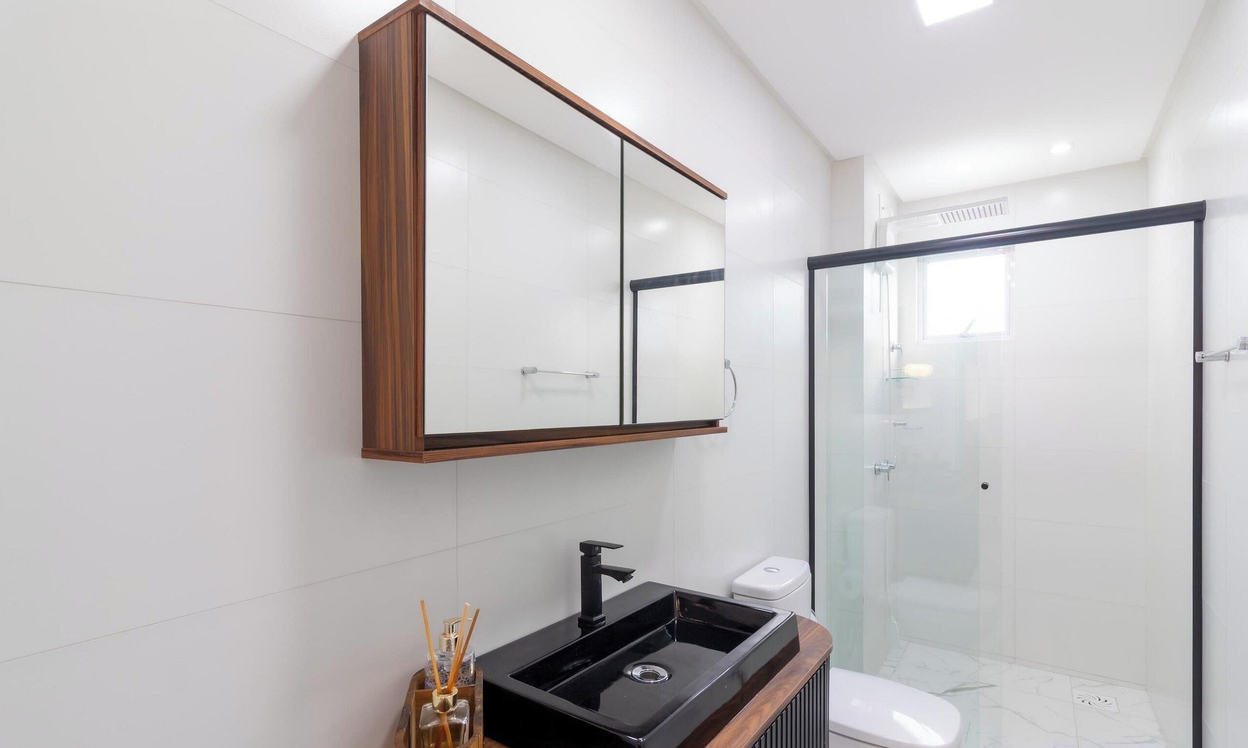 A modern bathroom with a glass shower enclosure, a black sink, and a white toilet.