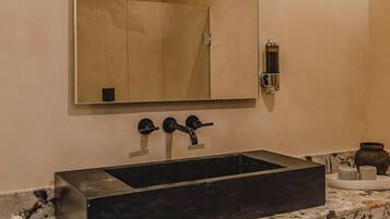 A bathroom with a rectangular sink, a large mirror, and a wall-mounted faucet.