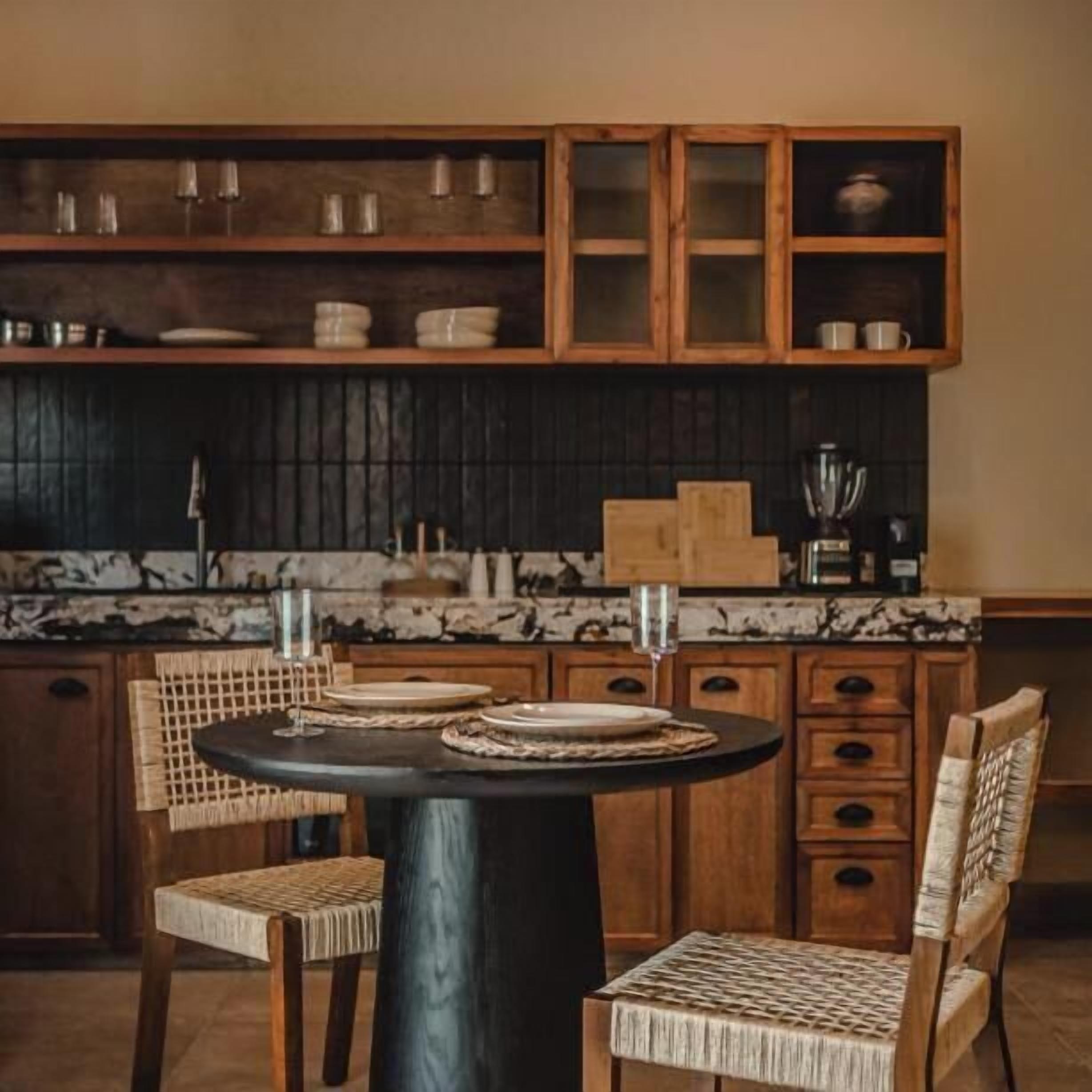 A kitchen with a round table, wooden chairs, and cabinets with glass doors.
