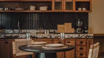 A kitchen with a round table, wooden chairs, and cabinets with glass doors.