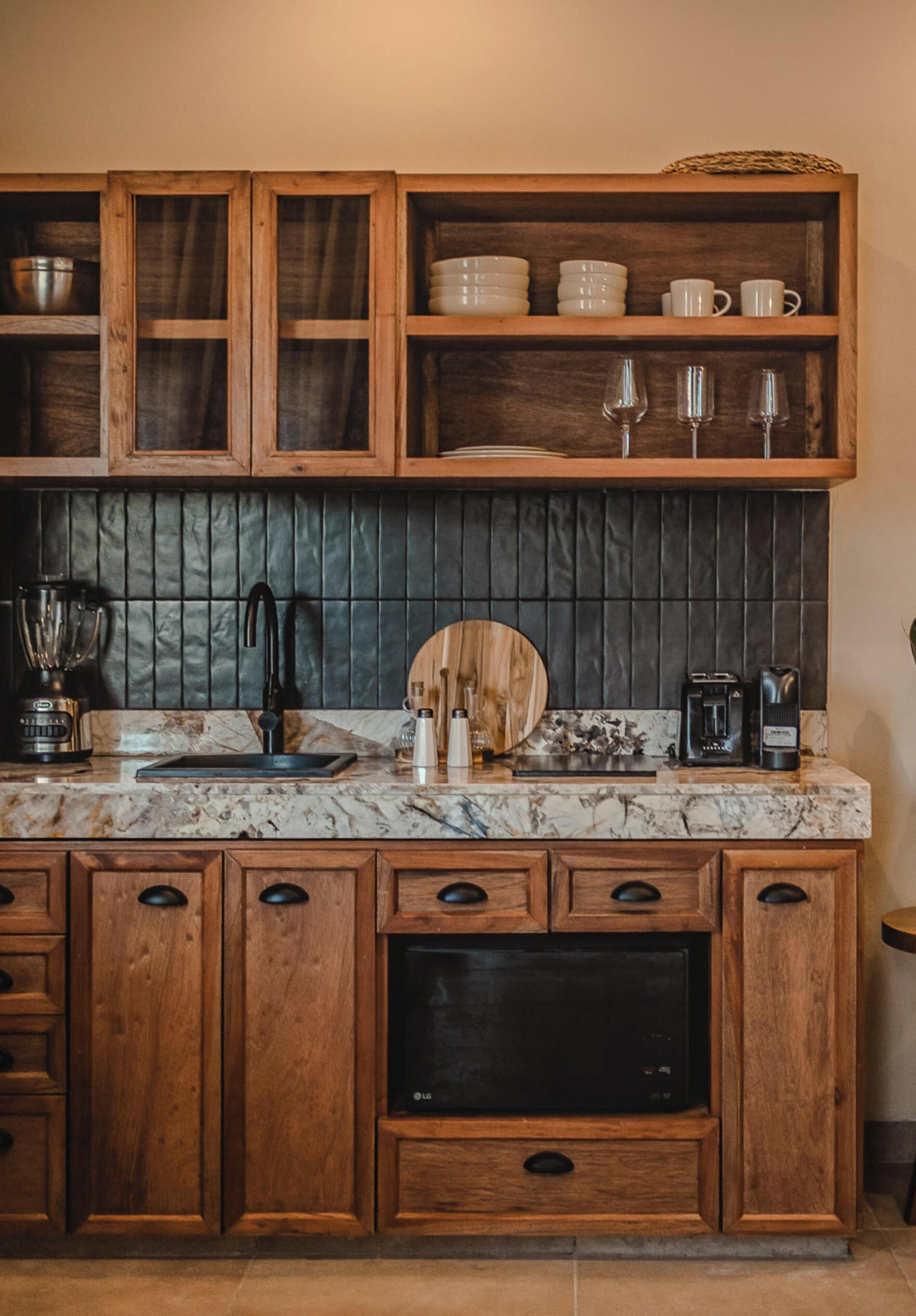 A kitchen with wooden cabinets, a marble countertop, and various kitchen appliances.