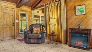 A wooden interior with a leather armchair, a table with a lamp, and a fireplace. - Red Canoe Cabin on the water in National Forest (Salt Springs)