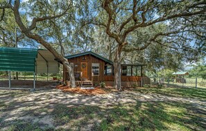 A rustic cabin with a wooden exterior, a porch, and a fenced yard. - Red Canoe Cabin on the water in National Forest (Salt Springs)