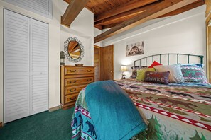 A bedroom with a bed, a dresser, a mirror, and a door. - Red Canoe Cabin on the water in National Forest (Salt Springs)