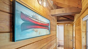 Ein Holzinterieur mit einem gerahmten Kunstwerk von roten Kanus an der Wand, einer Lampe und einer sichtbaren Badezimmertür.