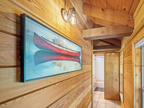 Ein Holzinterieur mit einem gerahmten Kunstwerk von roten Kanus an der Wand, einer Lampe und einer sichtbaren Badezimmertür.