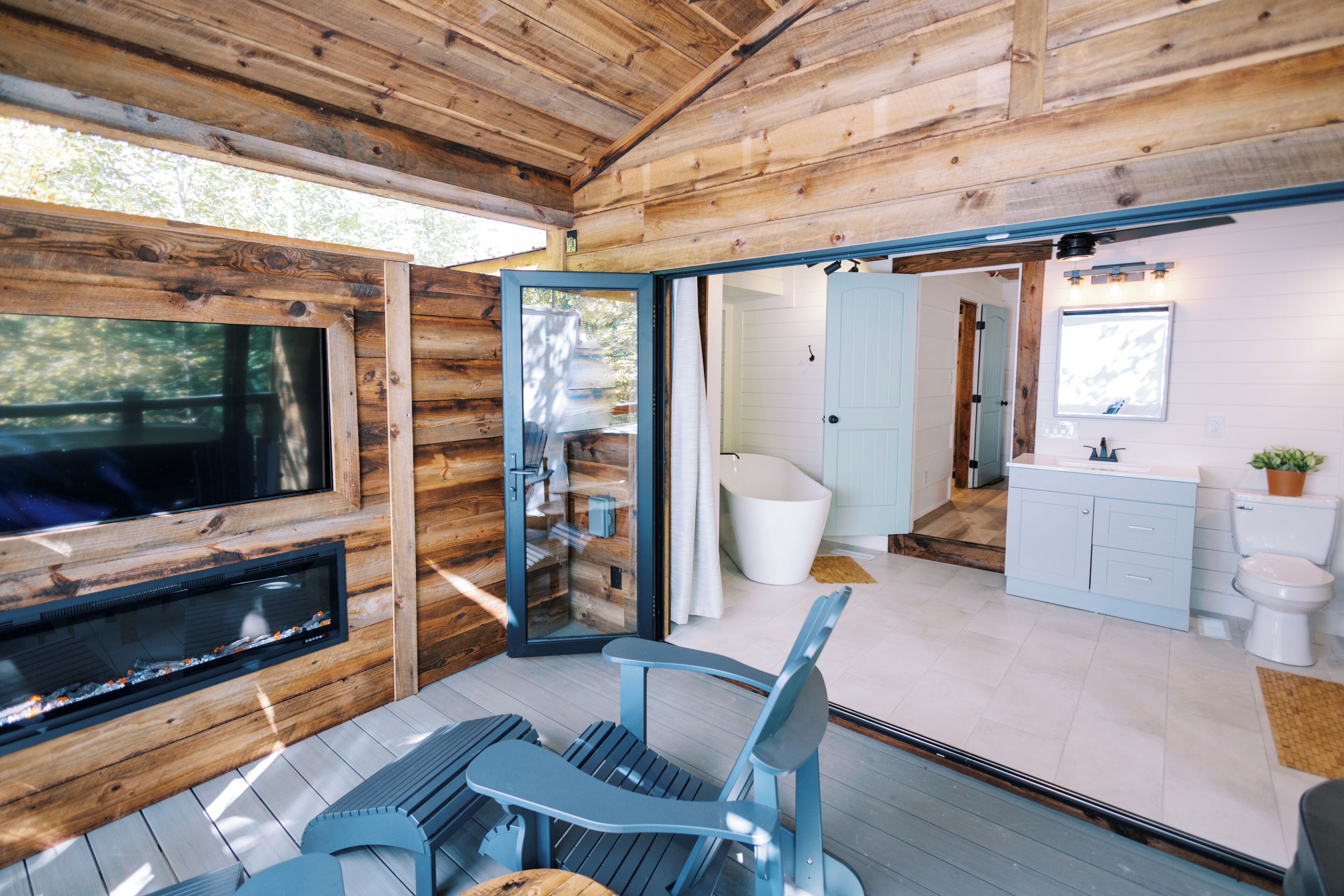 A modern cabin interior with a wooden exterior, a fireplace, a seating area, and a bathroom with a white toilet and sink.