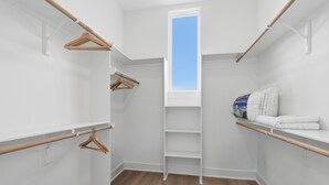 A walk-in closet with wooden hangers, a white shelf, and a skylight. - New Build Modern 3BR HTX Home • King Beds • Parking • Pet Friendly (Houston)