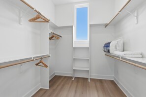 A walk-in closet with wooden hangers, a white shelf, and a skylight. - New Build Modern 3BR HTX Home • King Beds • Parking • Pet Friendly (Houston)