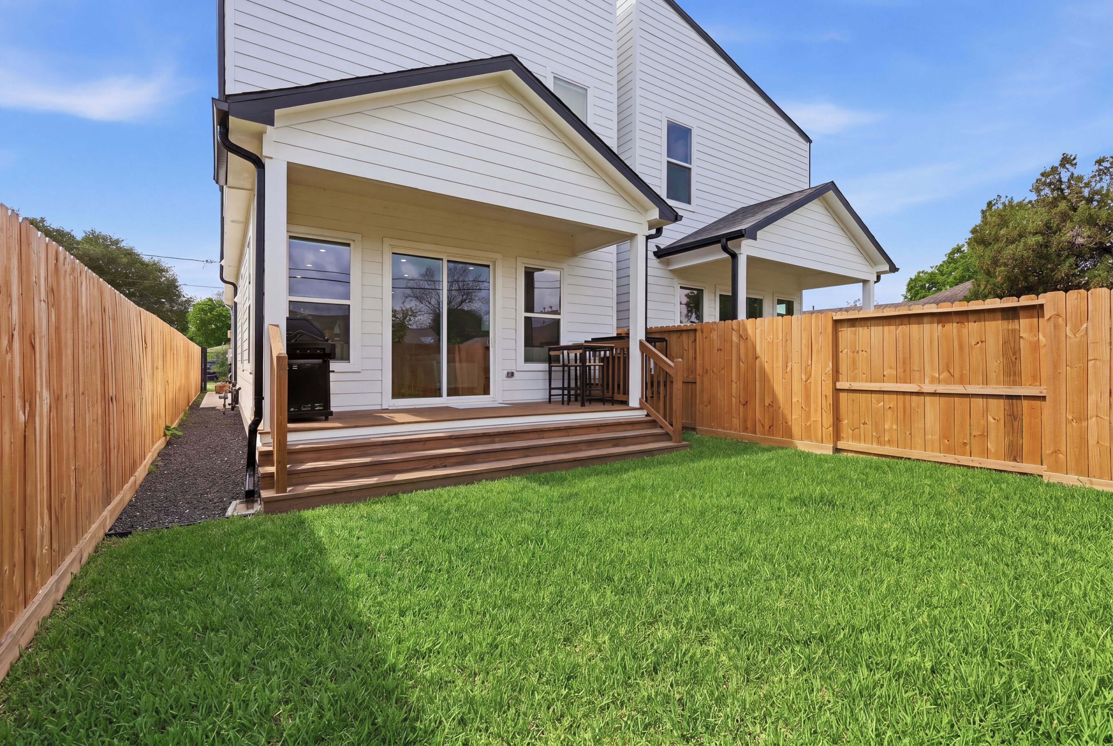 A two-story house with a covered porch and a fenced backyard.
