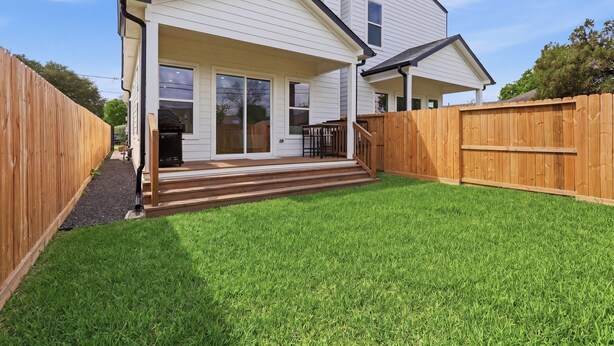 A two-story house with a covered porch and a fenced backyard. - New Build Modern 3BR HTX Home • King Beds • Parking • Pet Friendly (Houston)