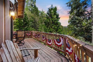 Eine Holzterrasse mit einer Bank und Stühlen, geschmückt mit amerikanischen Flaggen und Lichterketten.