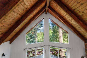 A room with a sloped wooden ceiling and large windows. - Lakeside Cavern | Lake Views | 3 Decks | Sleeps 8 (Lake Arrowhead)