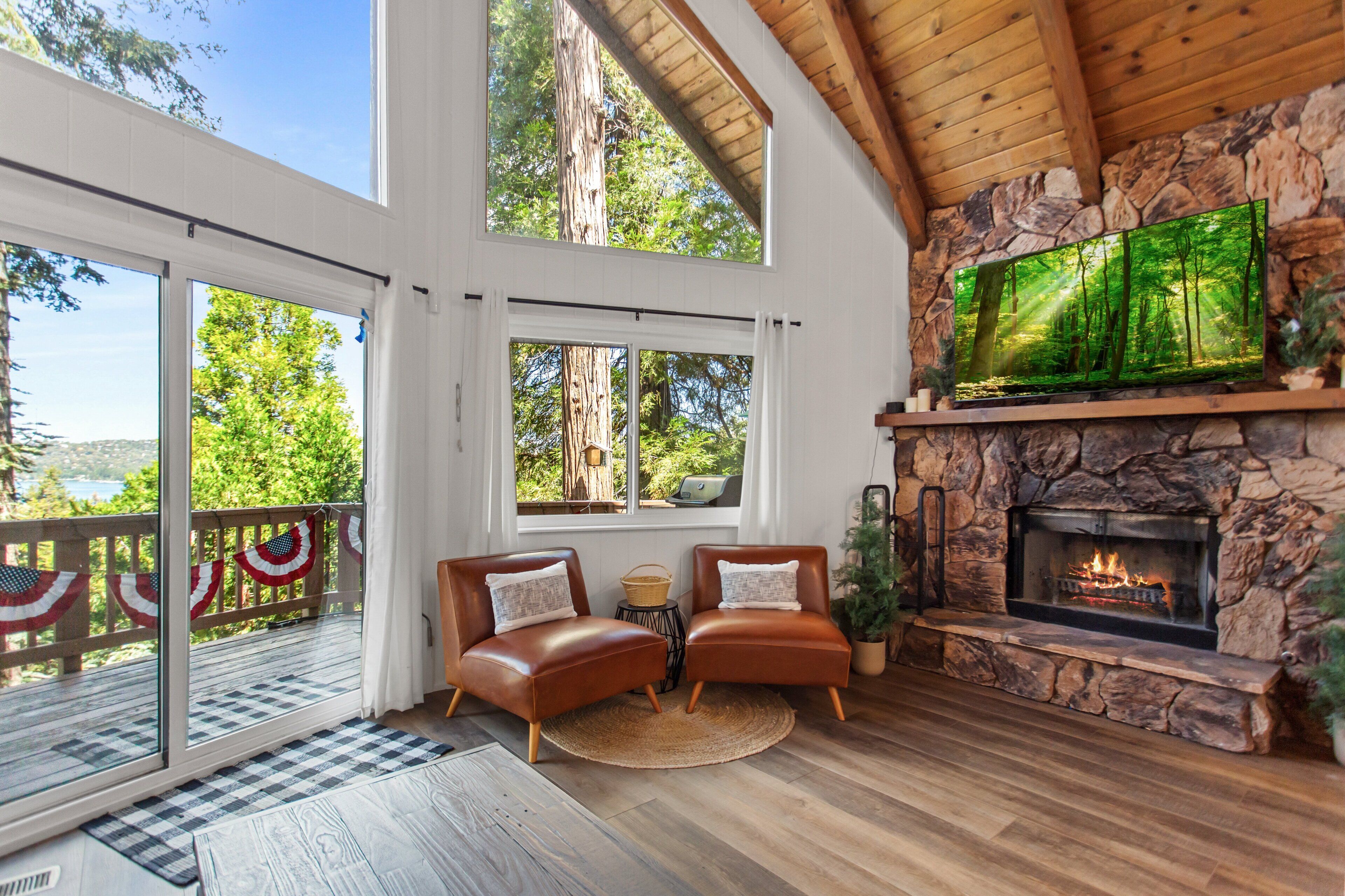 A spacious living area with a stone fireplace, two leather sofas, and a large TV screen.