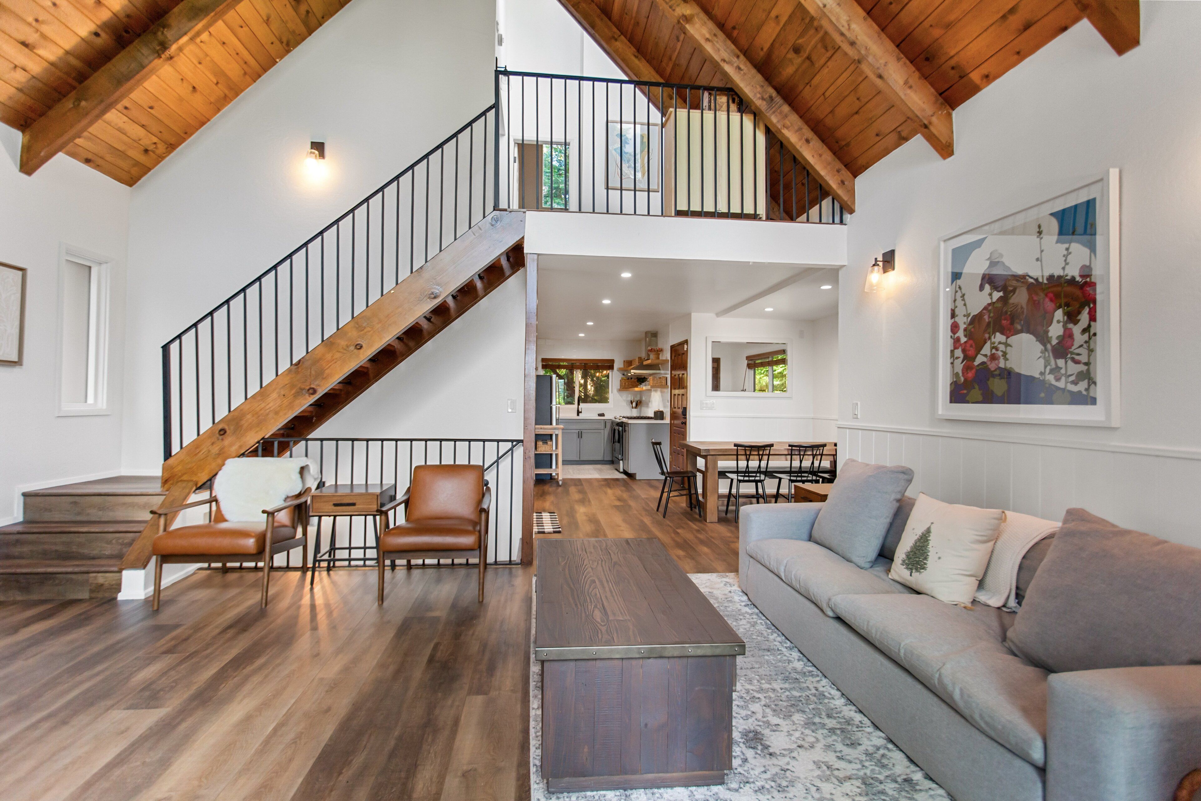 Ein geräumiger Wohnbereich mit einer Holztreppe, einem Essbereich und einer Küche im Hintergrund.