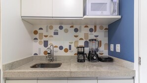 Una cocina con microondas, cafetera y licuadora sobre la encimera.