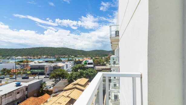 Un balcón con vistas a un pueblo costero, edificios y una colina al fondo.