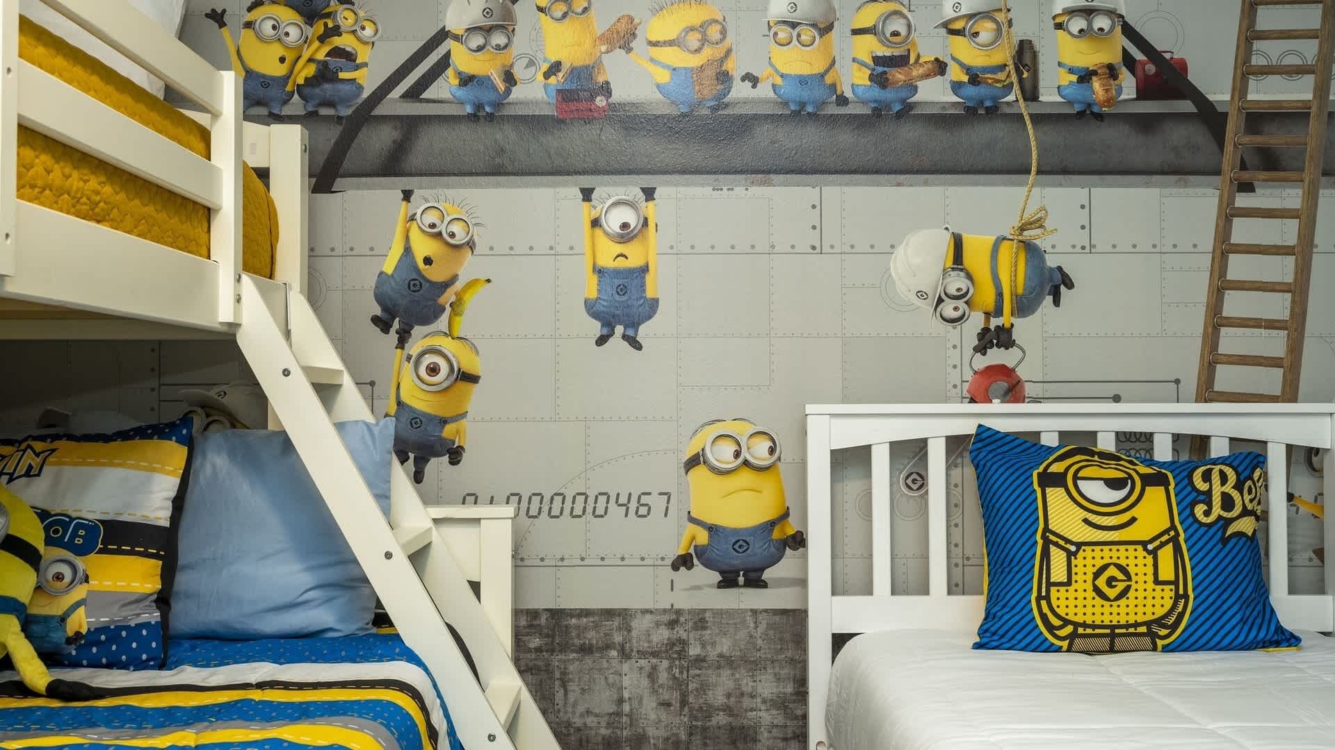 Une chambre d’enfant avec des lits superposés, un lit orné d’un oreiller à l’effigie des Minions et des autocollants des Minions sur les murs.
