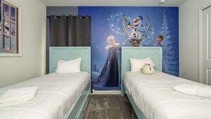 Ein Schlafzimmer mit zwei Betten, einer Wandmalerei mit Nachthimmel und einer Schneemann-Dekoration.