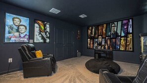 Ein Heimkino mit Liegesessel, Sitzsack und Filmplakaten an der Wand.