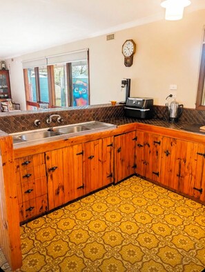 A kitchen with wooden cabinets, a sink, a coffee maker, and a clock on the wall. - Acheron Valley Riverbend Farmstay - Private Acheron River Access on 13 Acres (Acheron)