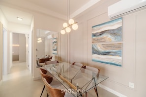 A modern dining area with a glass table, wooden chairs, and abstract wall art. - Apartment With Pool in Downtown Floripa Lgd0201 (Florianópolis)