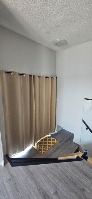 Ein Zimmer mit Duschbereich, Holzboden und weißer Wand.