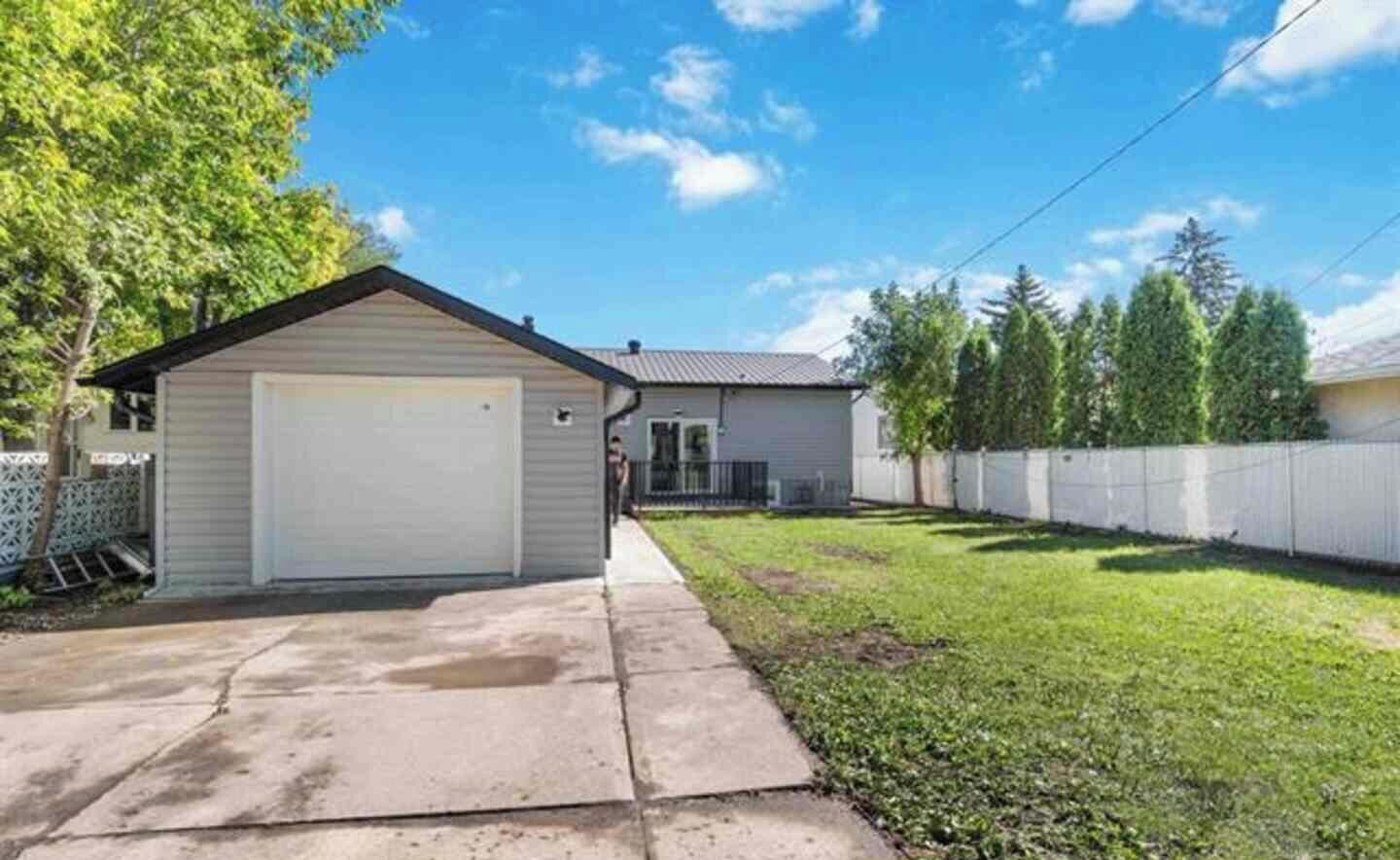A residential property with a garage, a lawn, and a fence.