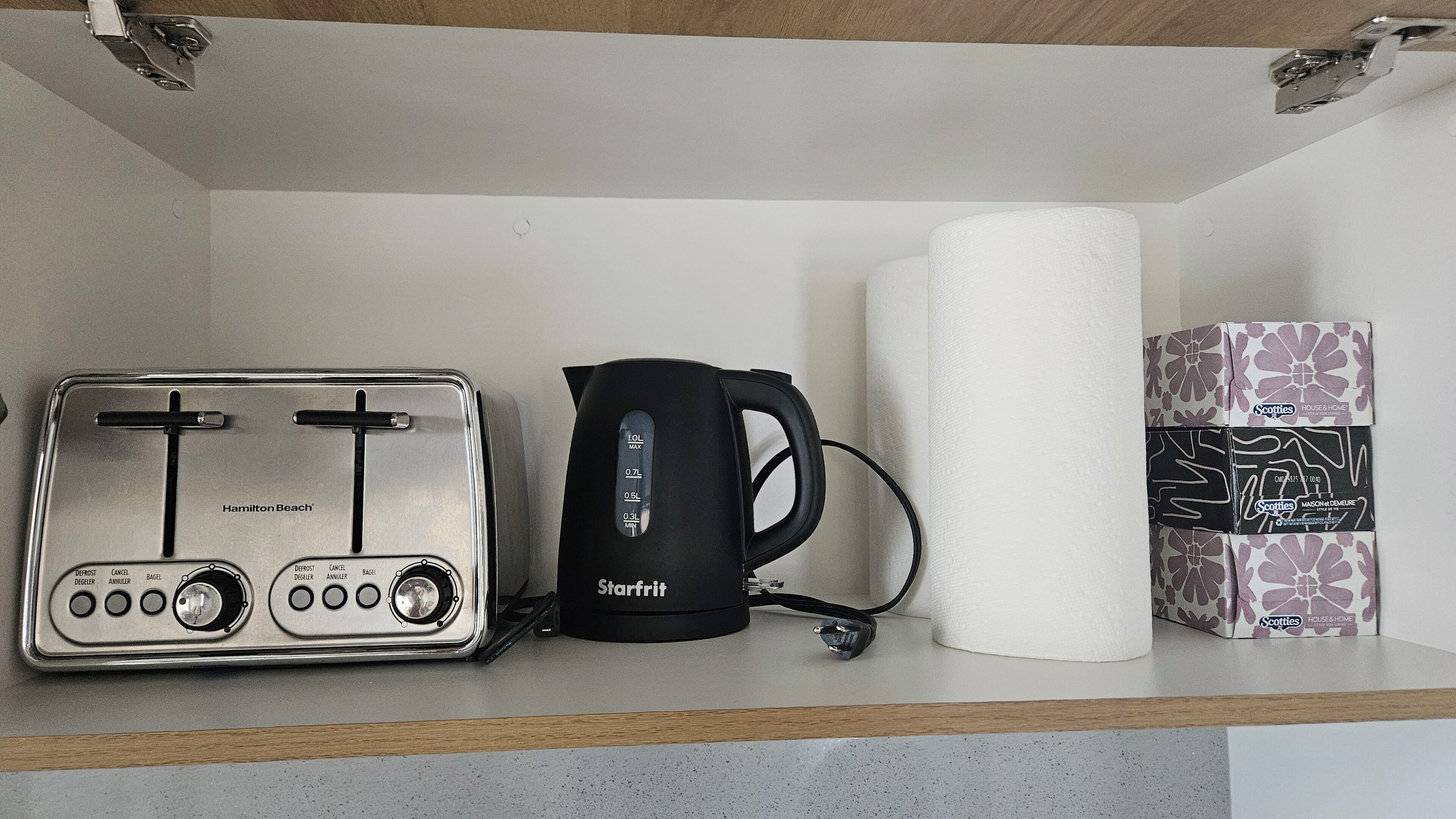 Een aanrecht met een Hamilton Beach-toaster, een Starfrit waterkoker en een pak keukenpapier.