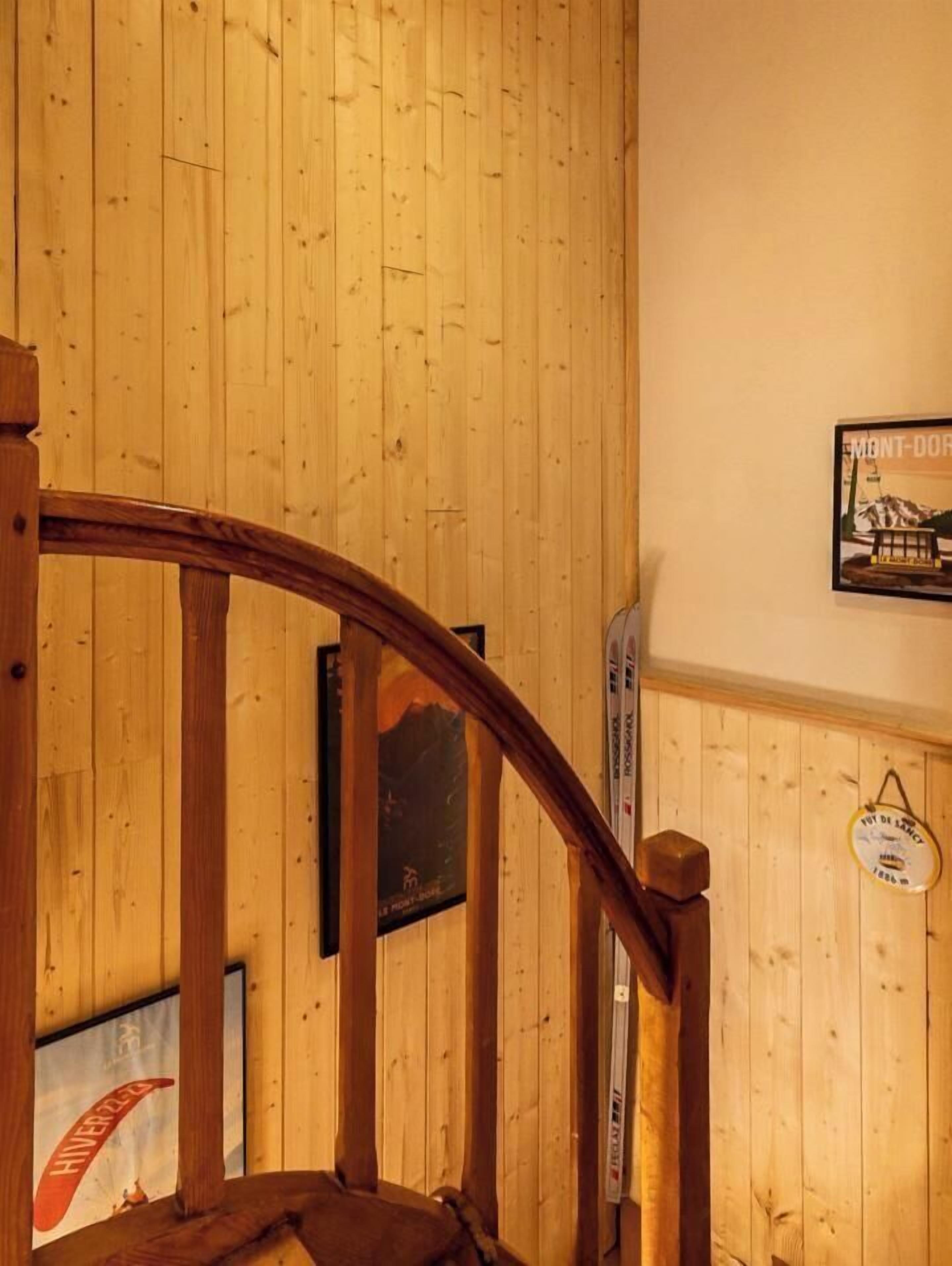 Eine Holztreppe mit Handlauf, ein gerahmtes Bild an der Wand und ein kleines Schild.