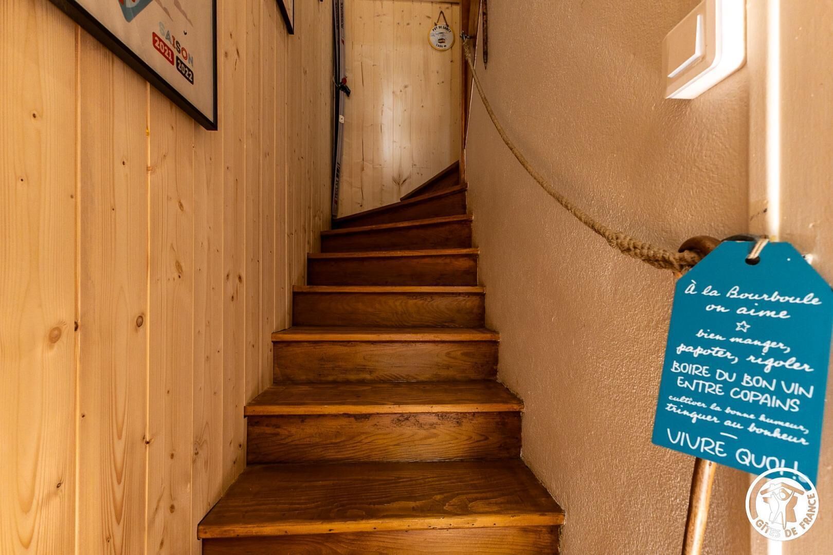 Un escalier en bois avec une pancarte accrochée au mur.