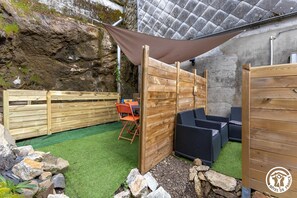 A patio area with a wooden fence, outdoor seating, and a shaded area. - The Val de Vendeix - LA BOURBOULE (LA BOURBOULE)