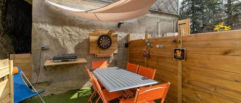 An outdoor patio with a table and chairs, a dartboard, and a wooden fence.