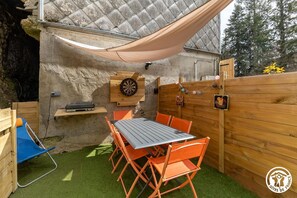 An outdoor patio with a table and chairs, a dartboard, and a wooden fence. - The Val de Vendeix - LA BOURBOULE (LA BOURBOULE)