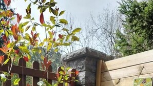 Zona de terrassa amb taula i cadires, tanca de fusta i plantes en testos.
