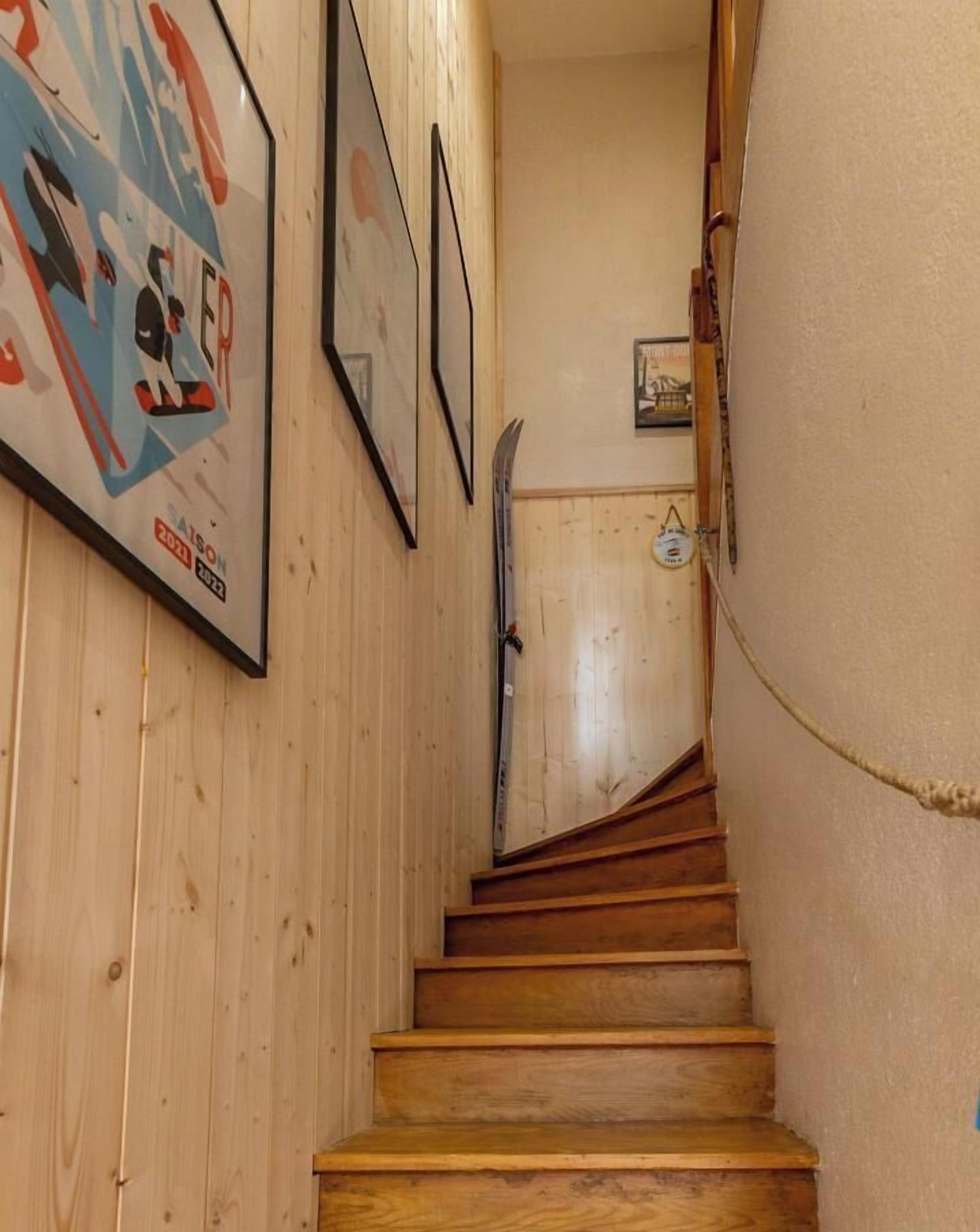 A wooden staircase with a handrail, wooden walls, and framed pictures.