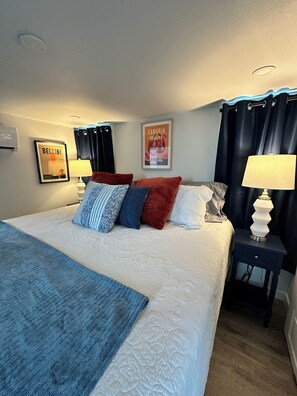 Ein Hotelzimmer mit einem großen Bett, zwei Nachttischen mit Lampen, einem gerahmten Bild an der Wand und einem Fenster mit Vorhängen.