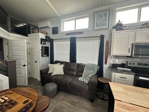 Ein kompakter Wohnbereich mit Sofa, Esstisch, Küchenzeile und Treppe.
