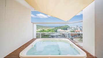 Banheira de hidromassagem numa varanda de madeira com vista para a cidade.