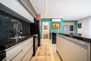 A modern kitchen with a granite countertop, stainless steel sink, and a black refrigerator. - Penthouse With Ocean View Ingleses Mhc0306 (Florianópolis)