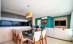 A modern kitchen with a central island, dining chairs, a sofa, and a TV mounted on the wall. - Penthouse With Ocean View Ingleses Mhc0306 (Florianópolis)