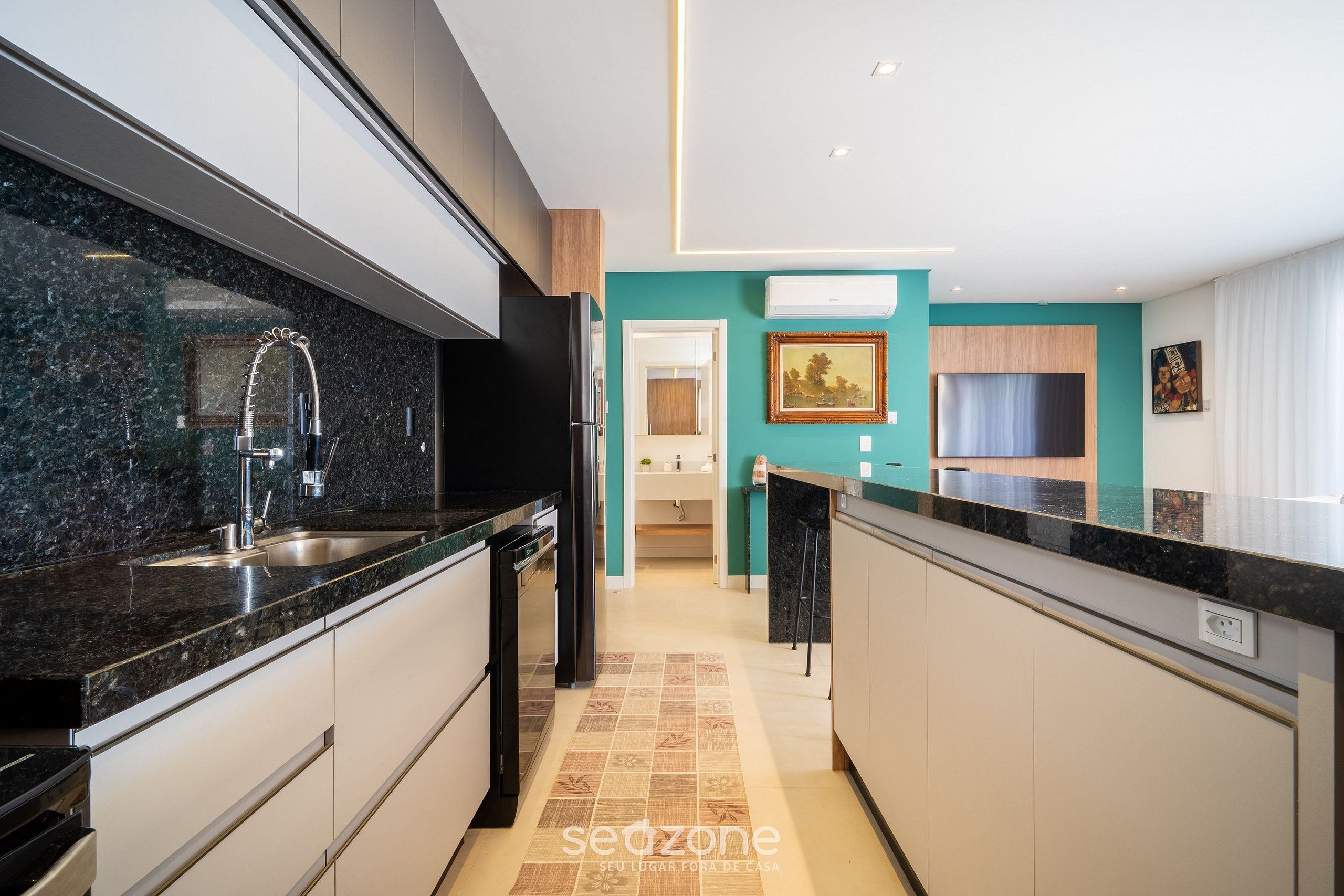 Una cocina moderna con encimera de granito, pileta de acero inoxidable y refrigerador negro.