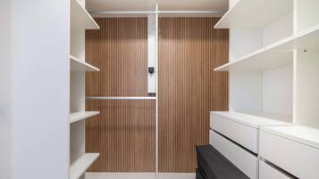 Un armario vestidor con paneles de madera, estanterías blancas y un banco.