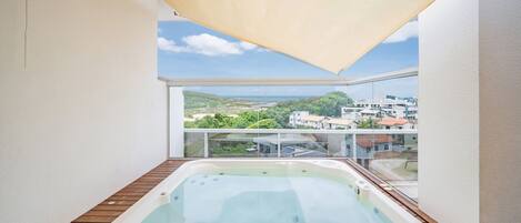 Un jacuzzi en una terraza de madera con vistas a un paisaje urbano.