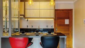 Una cocina moderna con una isla central, dos lámparas colgantes y una puerta de madera.