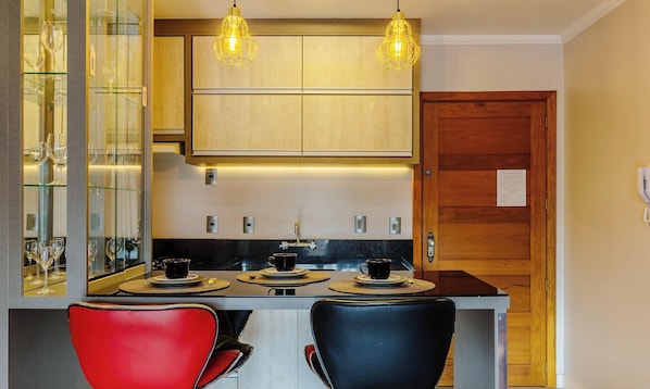 A modern kitchen with a central island, two pendant lights, and a wooden door. - Beautiful Studio in Gramado Mdc0214 (Gramado)
