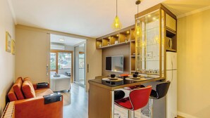 Una cocina moderna con una isla central, asientos tipo bar y un área de comedor con televisor.