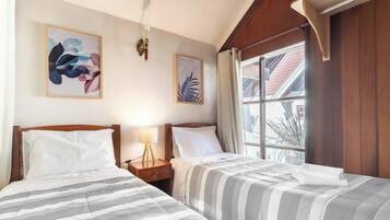 Una habitación de hotel con dos camas, una mesita de noche con lámpara y obras de arte en las paredes.